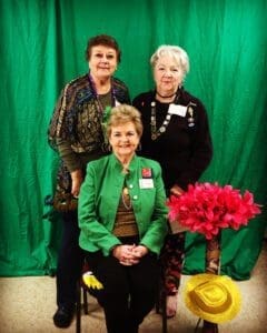 Three women in green and black outfits posing for a picture.