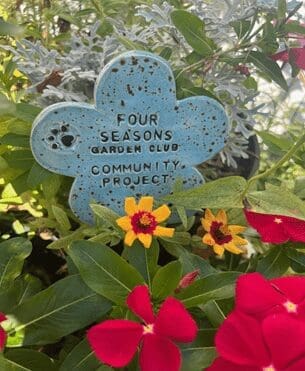 A blue flower with the words " four seasons garden club community project ".