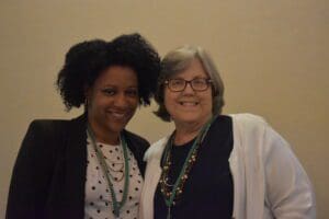Two women standing next to each other smiling.