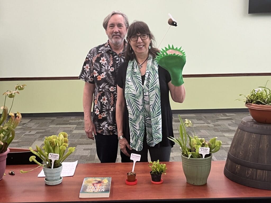 A man and woman standing in front of potted plants.