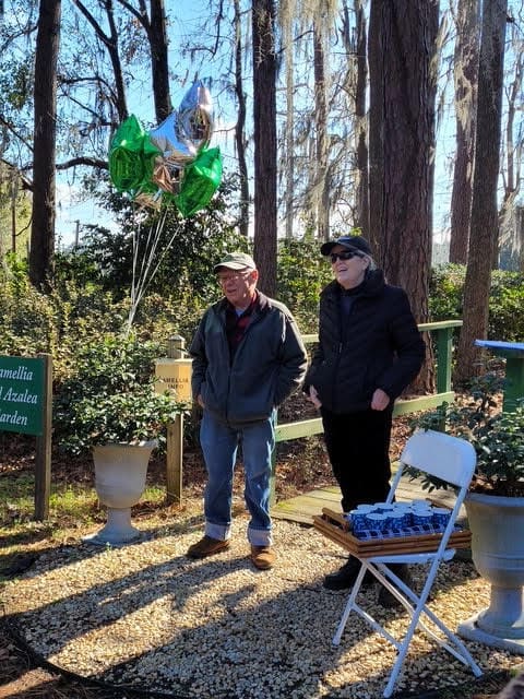 Two people standing in a forest with balloons.