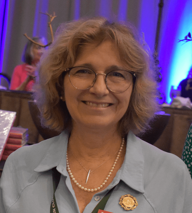 A smiling woman with glasses at a formal event.