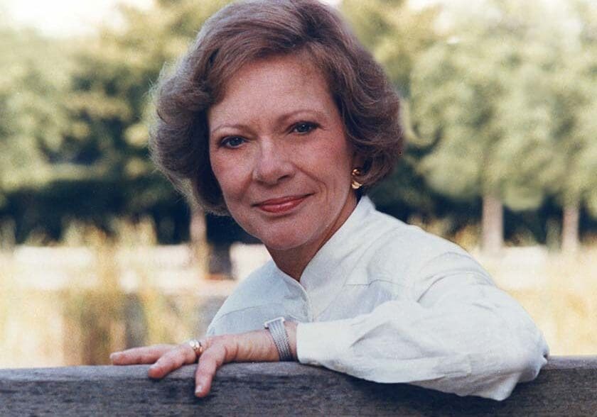 Smiling woman leaning on wooden railing outdoors