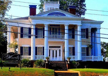 A large white house with blue shutters and a porch.