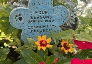 A blue flower with the words " four seasons garden club community project ".