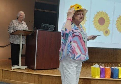 A woman wearing a yellow hat and holding up a balloon.